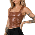 Brun lädertopp. En blond tjej poserar med en synlig tatuering på armen.