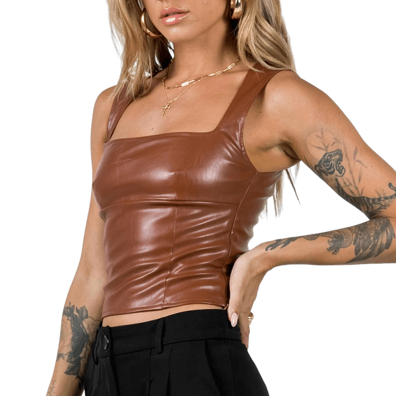 Brun lädertopp. En blond tjej poserar med en synlig tatuering på armen.